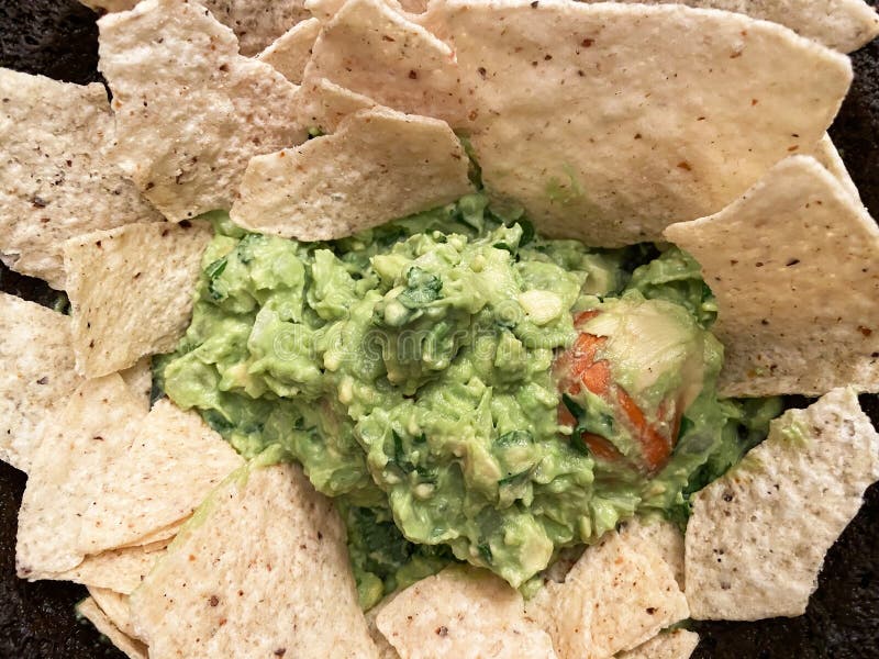 Photo of common mexican food that is consumed white watching football on tv. These are tortilla chips served with guacamole. Photo of common mexican food that is consumed white watching football on tv. These are tortilla chips served with guacamole.