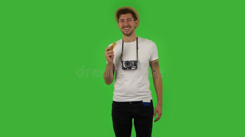 τουρίστας με καπέλο με κάμερα ρετρό και διαβατήριο στην τσέπη του αναζητά χρήματα και βρίσκει πιστωτική κάρτα. πράσινο