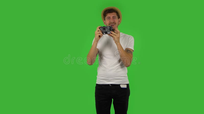τουρίστας στο καπέλο στις διακοπές τραβά φωτογραφίες σε μια κάμερα ρετρό. πράσινη οθόνη