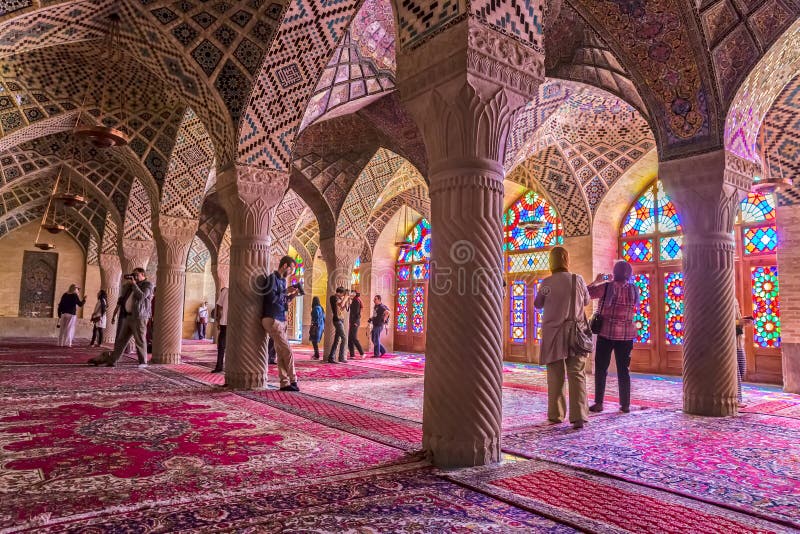SHIRAZ, IRAN - MAY 2, 2015: Visitors take a tour of the beautiful interior of the Nasir Al-Mulk Mosque or Pink Mosque a traditional mosque located in Goad-e-Araban place. SHIRAZ, IRAN - MAY 2, 2015: Visitors take a tour of the beautiful interior of the Nasir Al-Mulk Mosque or Pink Mosque a traditional mosque located in Goad-e-Araban place.