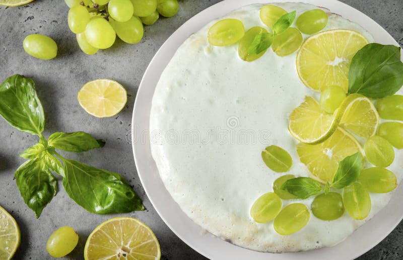 1 cake decorated with grapes, lime slices, and green Basil on a gray background, baking, cream, pie, top view, citrus. 1 cake decorated with grapes, lime slices, and green Basil on a gray background, baking, cream, pie, top view, citrus