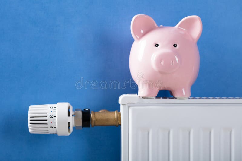 Τράπεζα Piggy στη θέρμανση του θερμαντικού σώματος στοκ εικόνες
