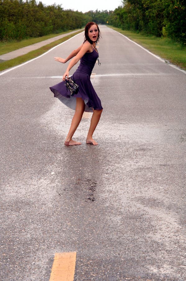 A scared, surprised girl running down a deserted street in the rain. A scared, surprised girl running down a deserted street in the rain