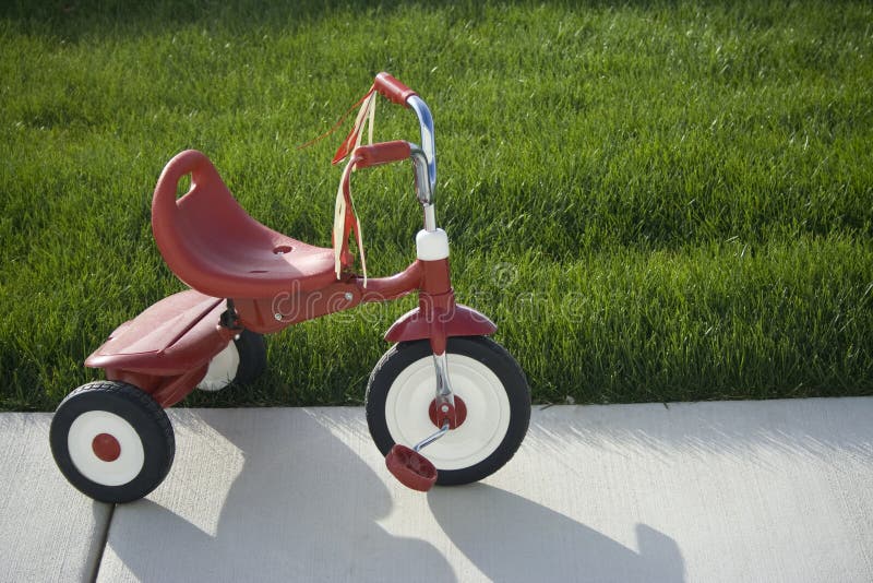 A single red tricycle left out in the yard. Is it a safe neighborhood. A single red tricycle left out in the yard. Is it a safe neighborhood