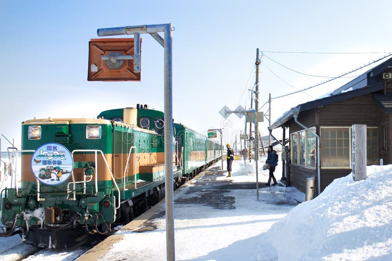 HOKKAIDO, JAPAN-1 FEB. 2013: Train in Hokkaido, Japan on Feb, 1, 2013, a snow day. Unidentified Japanese train conductor observes passenger before giving a sign to move the train. HOKKAIDO, JAPAN-1 FEB. 2013: Train in Hokkaido, Japan on Feb, 1, 2013, a snow day. Unidentified Japanese train conductor observes passenger before giving a sign to move the train.