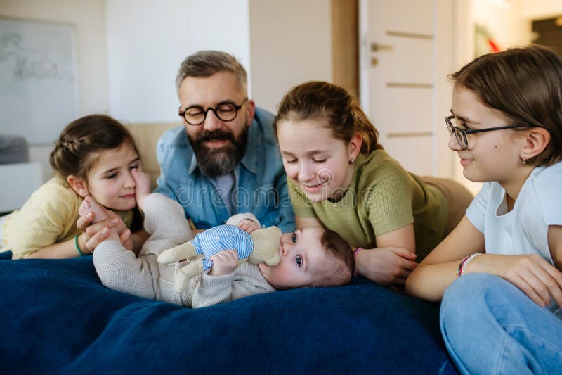 Τρεις αδερφές κοιτούν νεογέννητο αδερφό σε πατεράδες. στοκ φωτογραφίες με δικαίωμα ελεύθερης χρήσης