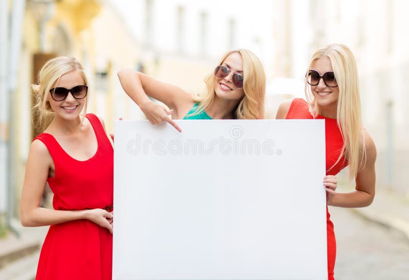 Τρεις ευτυχείς ξανθές γυναίκες με τον κενό λευκό πίνακα στοκ εικόνα με δικαίωμα ελεύθερης χρήσης Τρεις ευτυχείς ξανθές γυναίκες με τον κενό λευκό πίνακα στοκ εικόνα με δικαίωμα ελεύθερης χρήσης