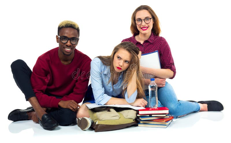 Τρεις ευτυχείς σπουδαστές που κάθονται με τα βιβλία, το lap-top και τις τσάντες