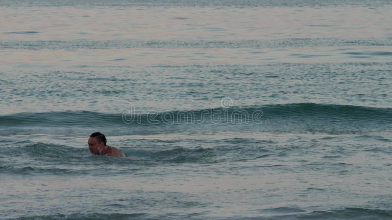 τρελός αστείος άνδρας προσποιείται ότι κολυμπάει σε ρηχά νερά κοντά στην ακτή