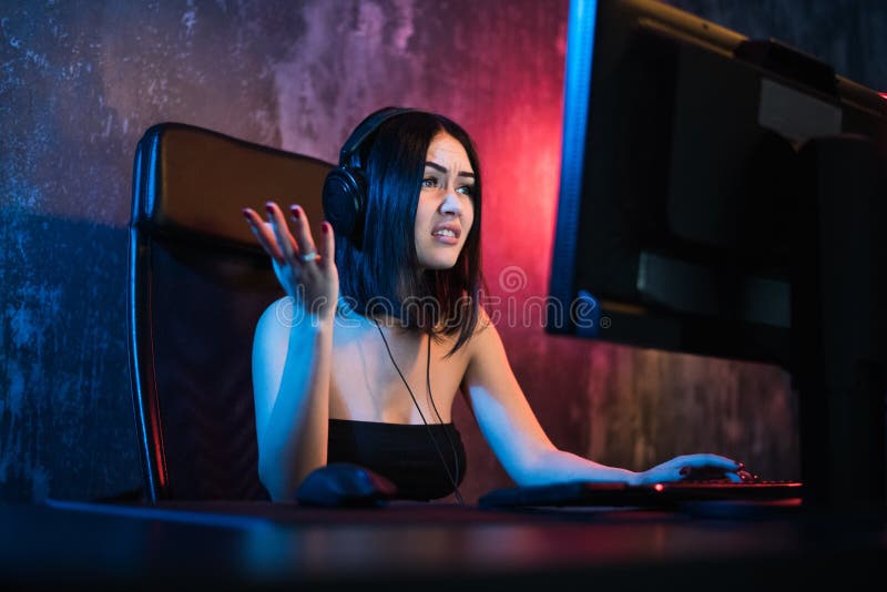 Τρομαγμένα gamer παιχνίδια παιχνιδιών στον υπολογιστή σας Μια συναισθηματική νέα γυναίκα στα ακουστικά παίζει τα παιχνίδια σε ένα στοκ εικόνα Τρομαγμένα gamer παιχνίδια παιχνιδιών στον υπολογιστή σας Μια συναισθηματική νέα γυναίκα στα ακουστικά παίζει τα παιχνίδια σε ένα στοκ εικόνα