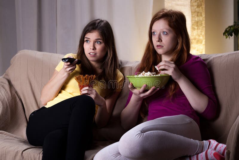 Young girls watching scary movie and eating popcorn. Young girls watching scary movie and eating popcorn