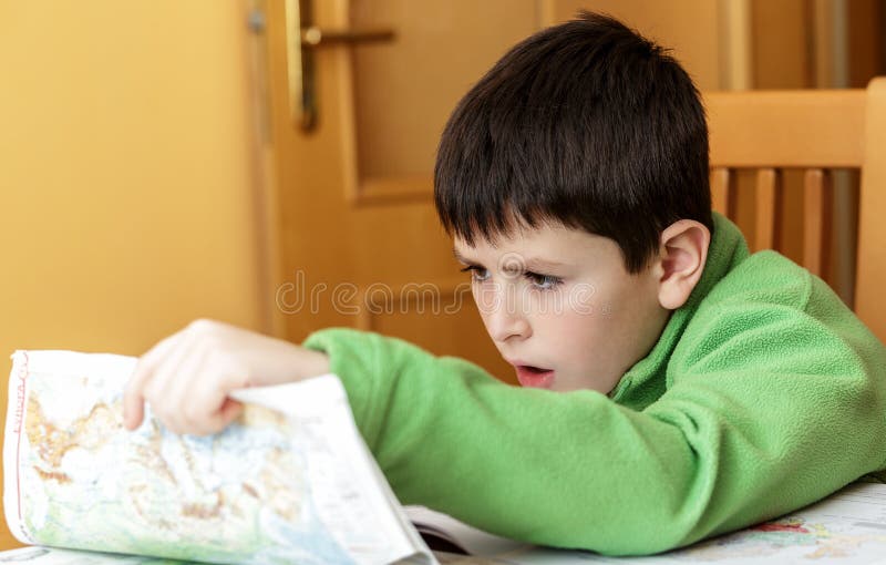 Bored and tired boy doing homework from school in workbook using worl map. Bored and tired boy doing homework from school in workbook using worl map