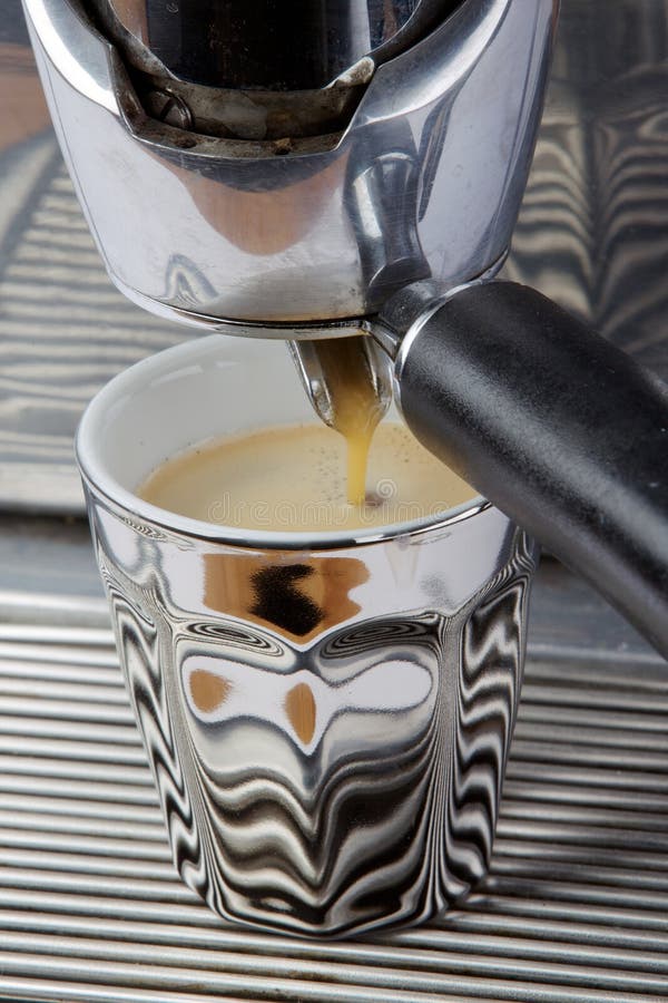 Chrome vintage espresso machine making a fresh cup of espresso into a silver / chrome cup. Chrome vintage espresso machine making a fresh cup of espresso into a silver / chrome cup