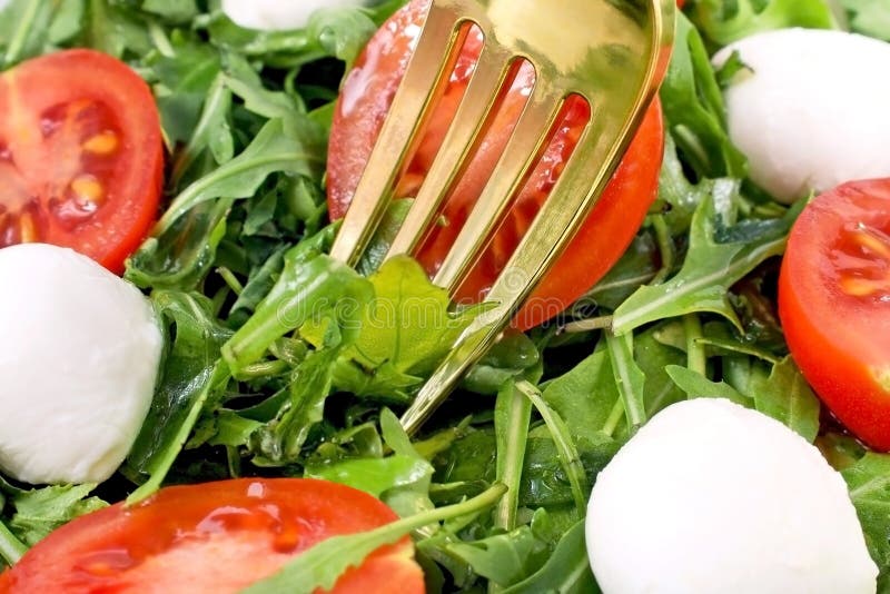 τρώω μια πράσινη σαλάτα με arugula αφήνει μπάλες μοτσαρέλα και ντομάτες κεράσι με ένα πιρούνι κοντά. στοκ φωτογραφίες με δικαίωμα ελεύθερης χρήσης τρώω μια πράσινη σαλάτα με arugula αφήνει μπάλες μοτσαρέλα και ντομάτες κεράσι με ένα πιρούνι κοντά. στοκ φωτογραφίες με δικαίωμα ελεύθερης χρήσης