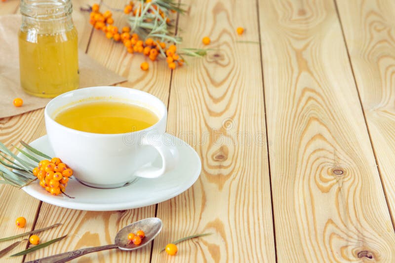Τσάι με τα πορτοκαλιά μούρα θάλασσα-buckthorn σε ένα φλυτζάνι και ένα οργανικό μέλι στοκ φωτογραφίες Τσάι με τα πορτοκαλιά μούρα θάλασσα-buckthorn σε ένα φλυτζάνι και ένα οργανικό μέλι στοκ φωτογραφίες