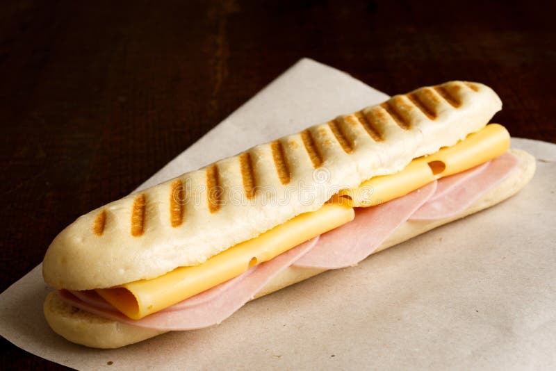 Τυρί και ψημένο ζαμπόν panini Σε καφετί χαρτί και το ξύλο στοκ φωτογραφία