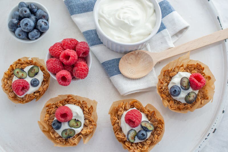 Υγιές σπίτι που γίνεται τα φλυτζάνια granola με το ελληνικά γιαούρτι και τα μούρα στοκ εικόνες
