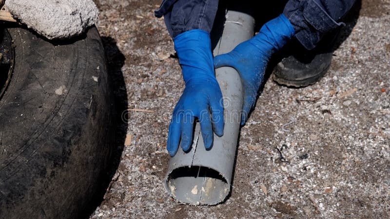 υδραυλικός με λαστιχένια γάντια κόβει κατά μήκος έναν πλαστικό σωλήνα αποχέτευσης. στοκ εικόνες