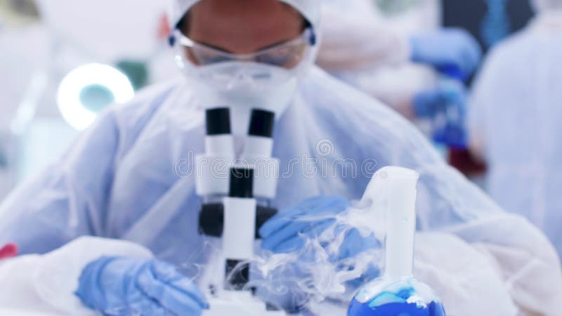 Υλικό χεριού χημικού που φοράει καλυμμένο εξοπλισμό σε σύγχρονο εργαστήριο