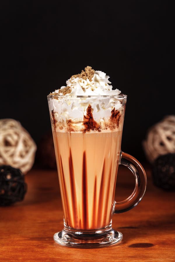 Υπέροχα σχεδιασμένος latte καφές macchiato με την κτυπημένη κρέμα και ψεκασμένος με το συντριμμένο halva, σε ένα σκοτεινό υπόβαθρ στοκ εικόνα με δικαίωμα ελεύθερης χρήσης Υπέροχα σχεδιασμένος latte καφές macchiato με την κτυπημένη κρέμα και ψεκασμένος με το συντριμμένο halva, σε ένα σκοτεινό υπόβαθρ στοκ εικόνα με δικαίωμα ελεύθερης χρήσης