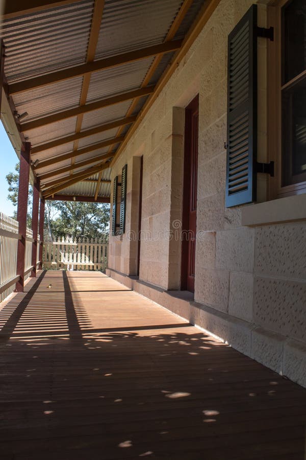 Υπαίθρια γέφυρα patio βεραντών του εξοχικού σπιτιού τούβλου ψαμμίτη με το φράκτη στύλων στην ηλιοφάνεια με τα δέντρα στο υπόβαθρο στοκ φωτογραφίες με δικαίωμα ελεύθερης χρήσης