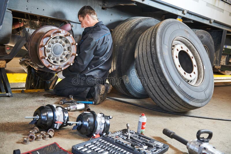 Truck repair service. Mechanic takes off tyre for brake replacement. Truck repair service. Mechanic takes off tyre for brake replacement