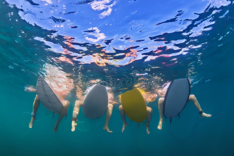 Υποβρύχια φωτογραφία των surfers που κάθονται στους πίνακες κυματωγών στοκ εικόνες