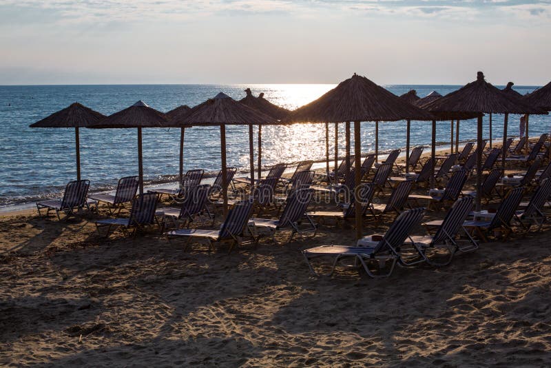Υπόλοιπος κόσμος των ξύλινων ομπρελών στην αμμώδη παραλία, θάλασσα κατά τη διάρκεια του ηλιοβασιλέματος στοκ φωτογραφία με δικαίωμα ελεύθερης χρήσης Υπόλοιπος κόσμος των ξύλινων ομπρελών στην αμμώδη παραλία, θάλασσα κατά τη διάρκεια του ηλιοβασιλέματος στοκ φωτογραφία με δικαίωμα ελεύθερης χρήσης