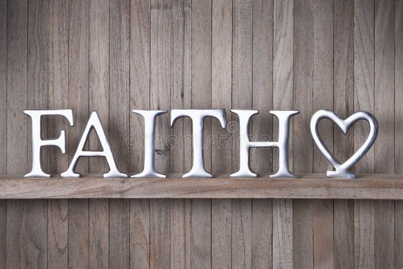 A rustic wood background with the word faith spelled out in metal letters and a love heart. A rustic wood background with the word faith spelled out in metal letters and a love heart.