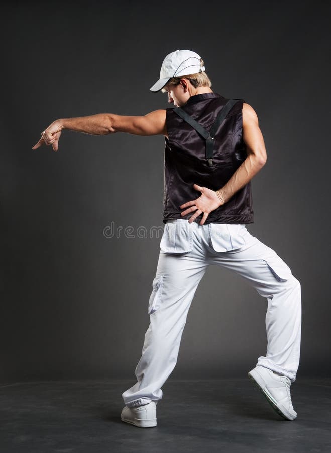 Hip-hop dancer in dance pointing against dark background. Hip-hop dancer in dance pointing against dark background