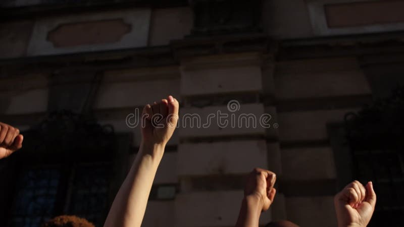 υψωμένες γροθιές στο φόντο τείχους μιας πόλης. άνθρωποι φωνάζουν συνθήματα. η διαμαρτυρία κατά του ρατσισμού. διαμαρτυρίες