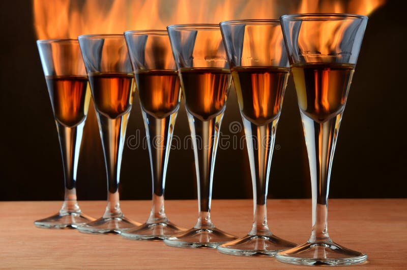 Amber colored alcohol beverage in classic style glasses on fire. Amber colored alcohol beverage in classic style glasses on fire.