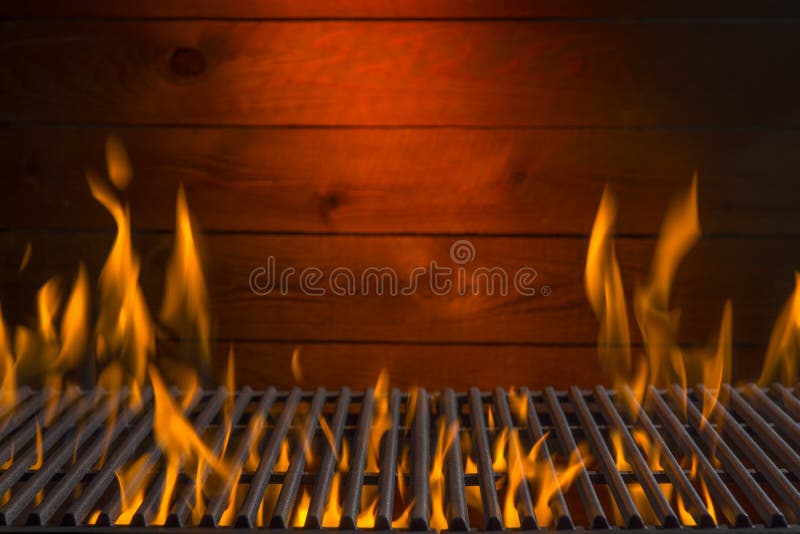 A hot grill with fire and a wood background. A hot grill with fire and a wood background.