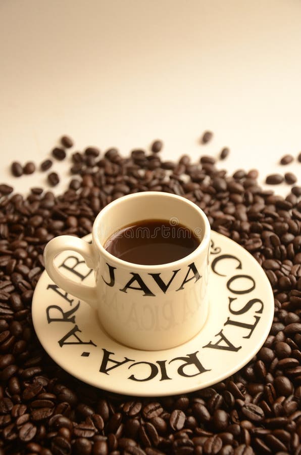 Small espresso cup of strong dark Costa Rican Arabica Coffee surrounded by fresh coffee beans with copyspace. Small espresso cup of strong dark Costa Rican Arabica Coffee surrounded by fresh coffee beans with copyspace.