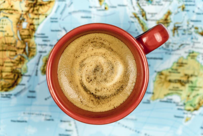 Φλυτζάνι του φρέσκου frothy καφέ σε έναν παγκόσμιο χάρτη στοκ εικόνες με δικαίωμα ελεύθερης χρήσης Φλυτζάνι του φρέσκου frothy καφέ σε έναν παγκόσμιο χάρτη στοκ εικόνες με δικαίωμα ελεύθερης χρήσης
