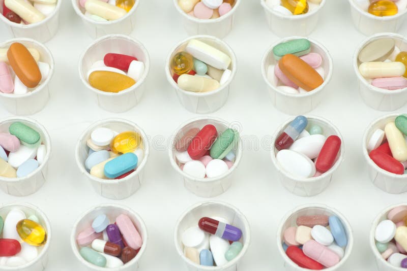 Many different assorted colorful pills in paper medication dosage cups. Many different assorted colorful pills in paper medication dosage cups.