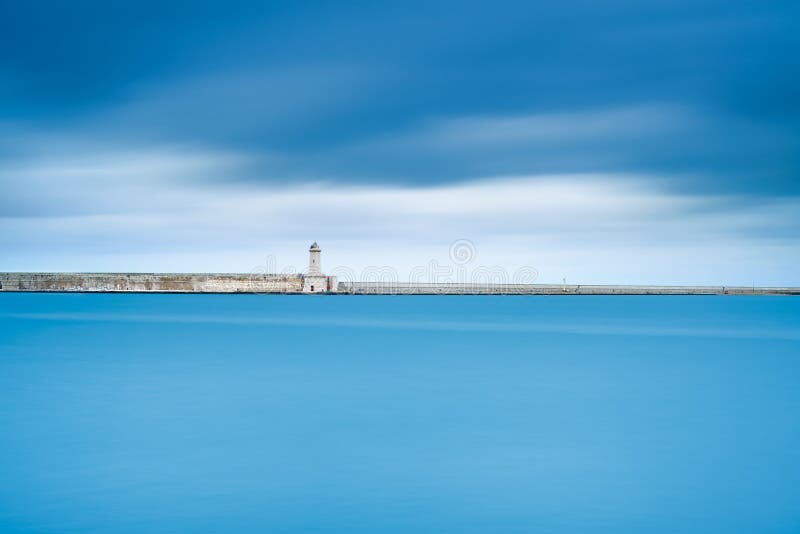 Livorno port lighthouse, breakwater and soft water under cloudy sky. Tuscany, Italy, Europe. Long exposure photography. Livorno port lighthouse, breakwater and soft water under cloudy sky. Tuscany, Italy, Europe. Long exposure photography.