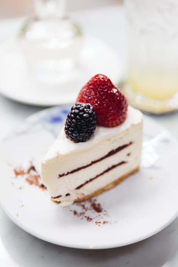 Φέτα cheesecake φραουλών του καλύμματος με τη φρέσκα φράουλα και το βατόμουρο Εξυπηρετημένος με τη σόδα mocktail και το σιρόπι στοκ εικόνα με δικαίωμα ελεύθερης χρήσης Φέτα cheesecake φραουλών του καλύμματος με τη φρέσκα φράουλα και το βατόμουρο Εξυπηρετημένος με τη σόδα mocktail και το σιρόπι στοκ εικόνα με δικαίωμα ελεύθερης χρήσης