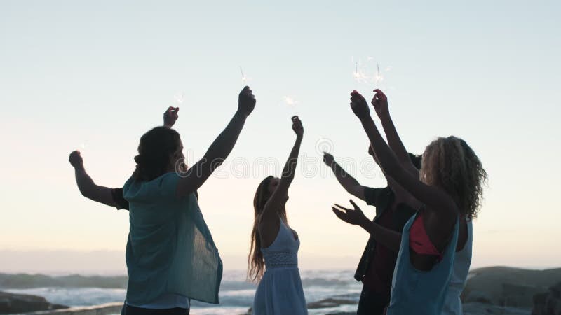 φίλοι κάνουν παρέα στην παραλία και λάτρεις για εορταστικό πάρτι ή ευτυχία για το νέο έτος μέχρι το ηλιοβασίλεμα. χαρούμενη ομάδα απόθεμα βίντεο