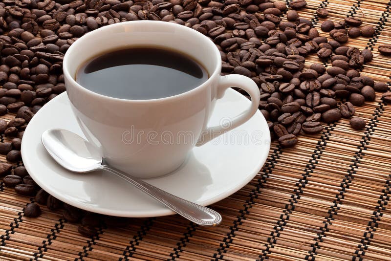 A cup of coffee and coffee beans on a bamboo mat. A cup of coffee and coffee beans on a bamboo mat.