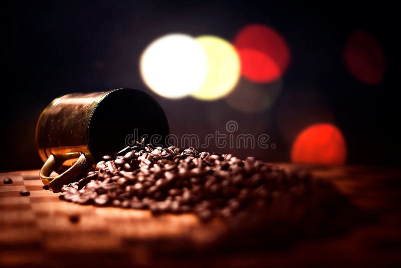 Coffee beans spilled out of a copper and brass cup. Coffee beans spilled out of a copper and brass cup