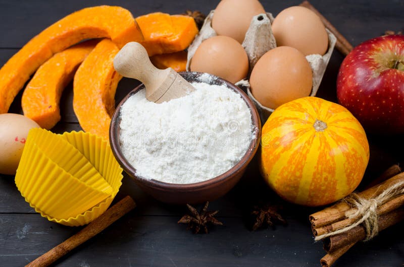 Autumn baking concept. Frame with pumpkin, apple, nuts, cinamon, egg and flour on the wood table. Cooking baking process with ingredients. top view. copy space. Autumn baking concept. Frame with pumpkin, apple, nuts, cinamon, egg and flour on the wood table. Cooking baking process with ingredients. top view. copy space