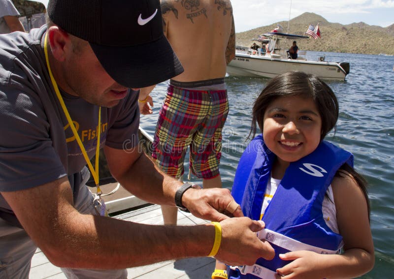 An adult shows a young girl proper way to wear, adjust, and fasten a life vest flotation device. An adult shows a young girl proper way to wear, adjust, and fasten a life vest flotation device.