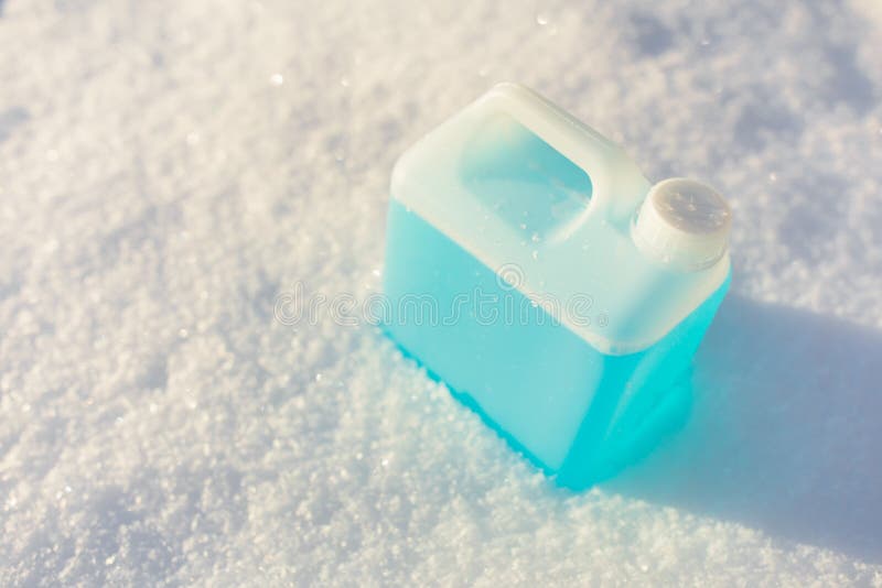 Bottle with blue non-freezing windshield washer fluid, snow background, close-up view. Bottle with blue non-freezing windshield washer fluid, snow background, close-up view