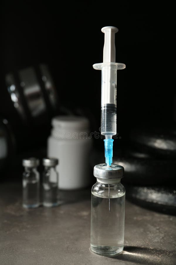 φιαλίδιο και σύριγγα με φάρμακο κοντά σε αθλητικό εξοπλισμό σε γκρίζο χώρο για κείμενο. έλεγχος εντοπισμού στοκ εικόνα