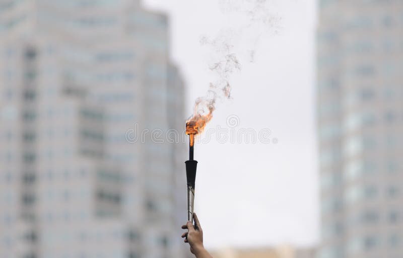 Human Hand holding a fire torch during a street festival in Toronto. Human Hand holding a fire torch during a street festival in Toronto.