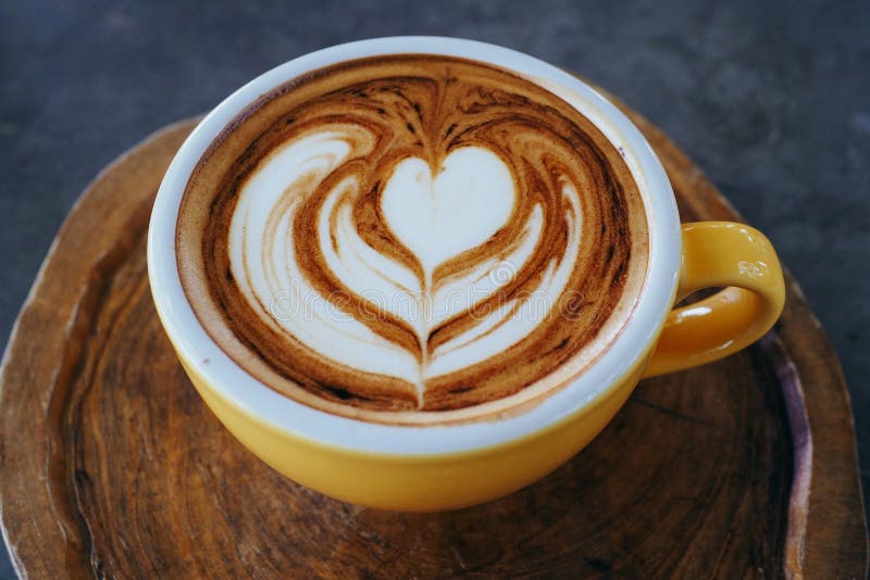 Φλυτζάνι του cappuccino με την όμορφη τέχνη latte στο ξύλινο πιάτο στοκ εικόνα με δικαίωμα ελεύθερης χρήσης Φλυτζάνι του cappuccino με την όμορφη τέχνη latte στο ξύλινο πιάτο στοκ εικόνα με δικαίωμα ελεύθερης χρήσης