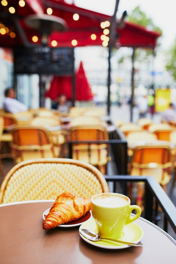 Cup of fresh hot coffee and traditional French croissant on table of Parisian outdoor cafe in Paris, France. Cup of fresh hot coffee and traditional French croissant on table of Parisian outdoor cafe in Paris, France