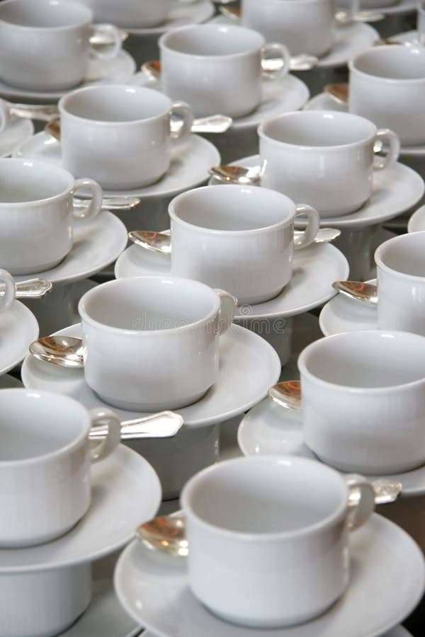 Stacks of coffee cups on saucers with silver teaspoons. Stacks of coffee cups on saucers with silver teaspoons