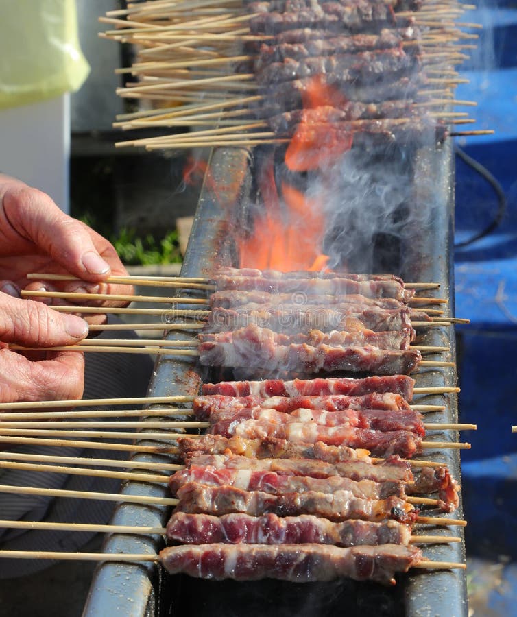 φλόγα της φωτιάς, ενώ μαγειρεύεται η αλατιρίνη το τυπικό ιταλικό πιάτο που φτιάχνεται με πρόβειο κρέας στοκ εικόνες